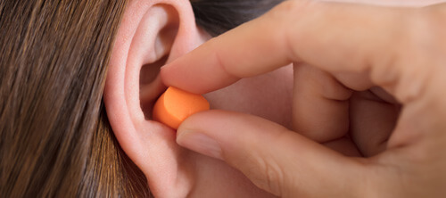 Frau setzt sich Gehörschutz ins Ohr